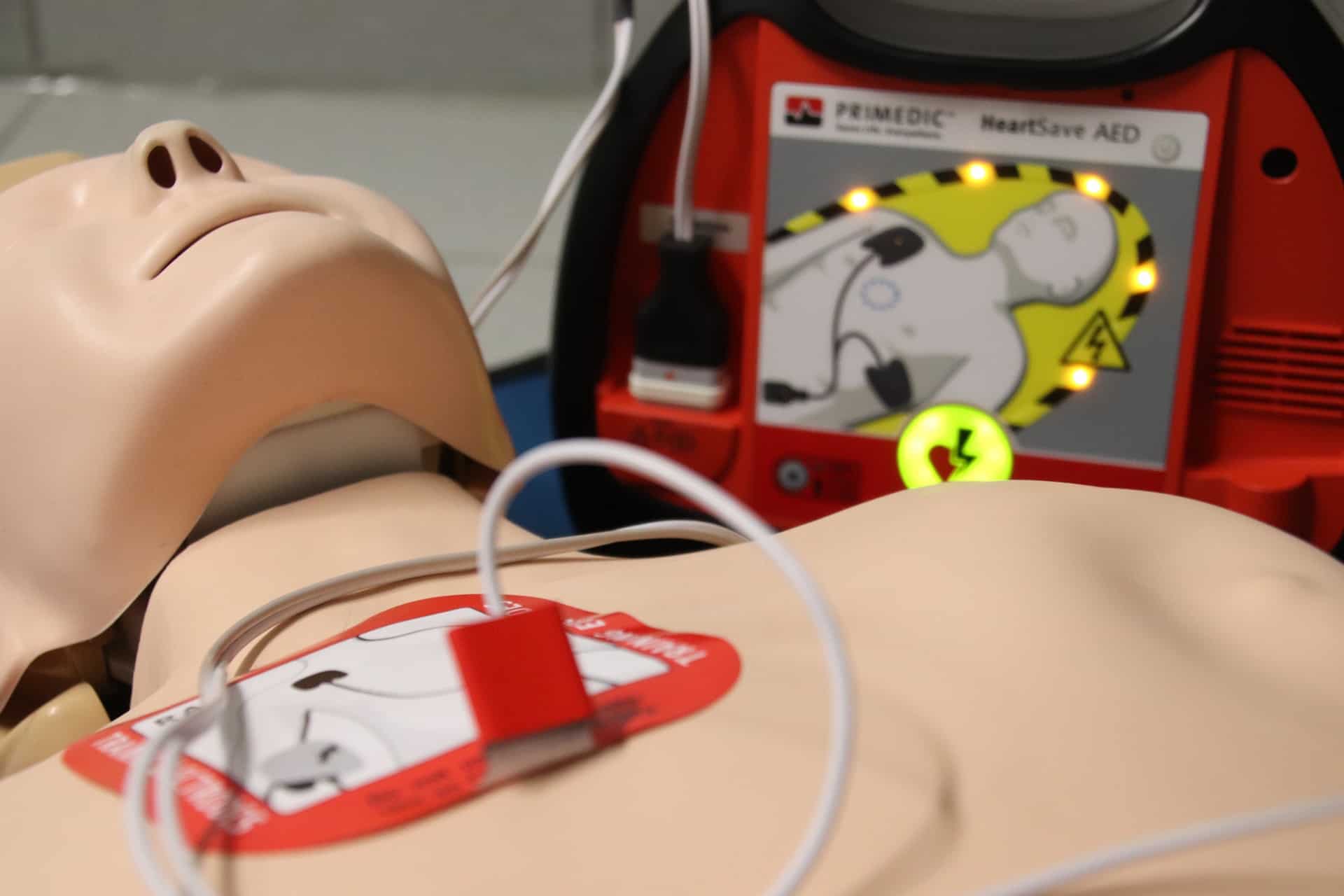 cpr mannequin with an aed machine attached to its chest, the machine is next to the mannequin